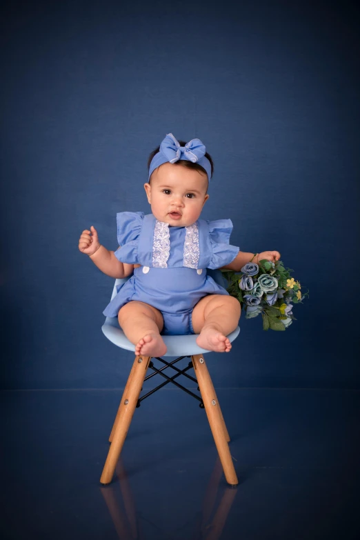 a baby is sitting on a chair with flowers in its lap