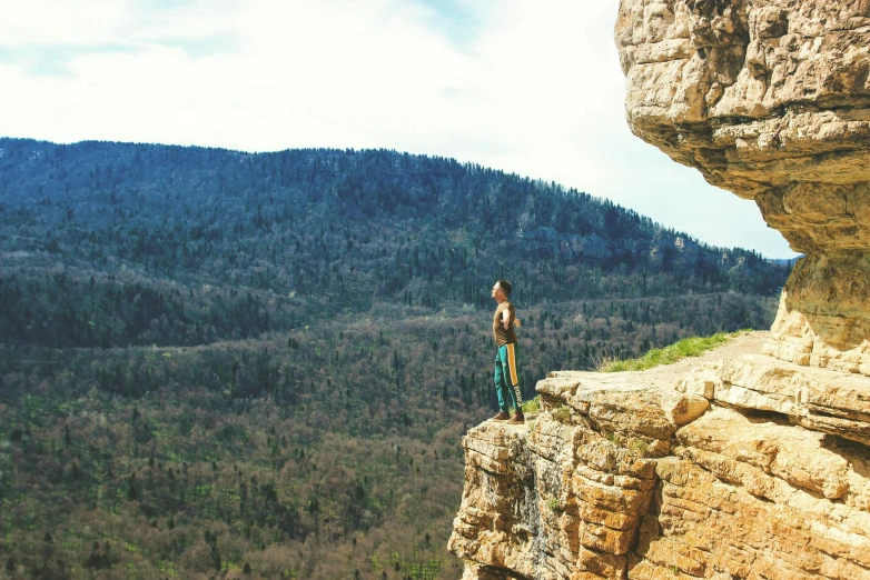 a woman standing on top of a cliff overlooking the mountains