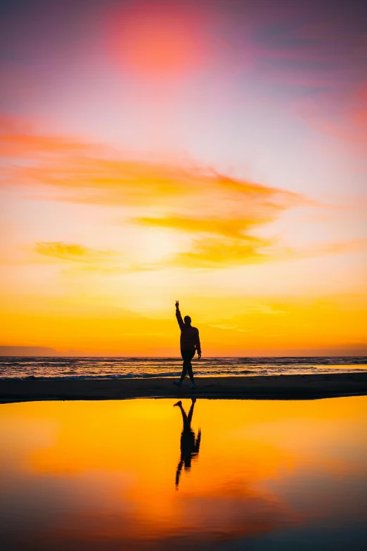 a man walking across the beach holding onto a kite