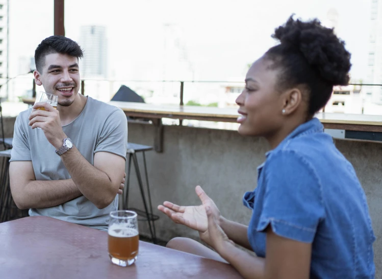 two people are sitting at a table with drinks and food