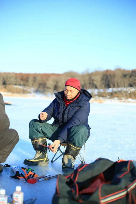 a man is cooking in the snow while another holds food