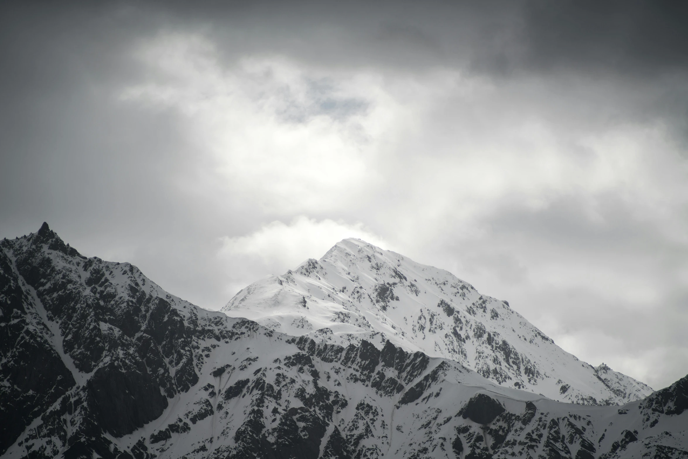 the mountains are almost covered in snow under a cloudy sky