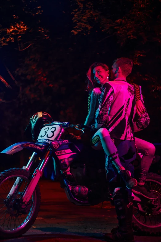 two women and a man on a motorbike in the dark
