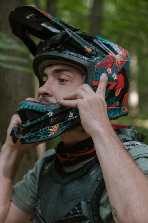 the man is talking on the cellphone while wearing a helmet