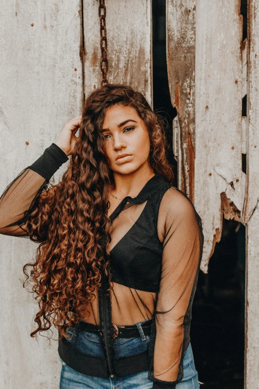 woman in  mesh top posing in front of the door of an old building