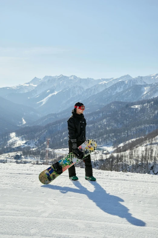 a person standing on a snow covered mountain slope holding a snowboard