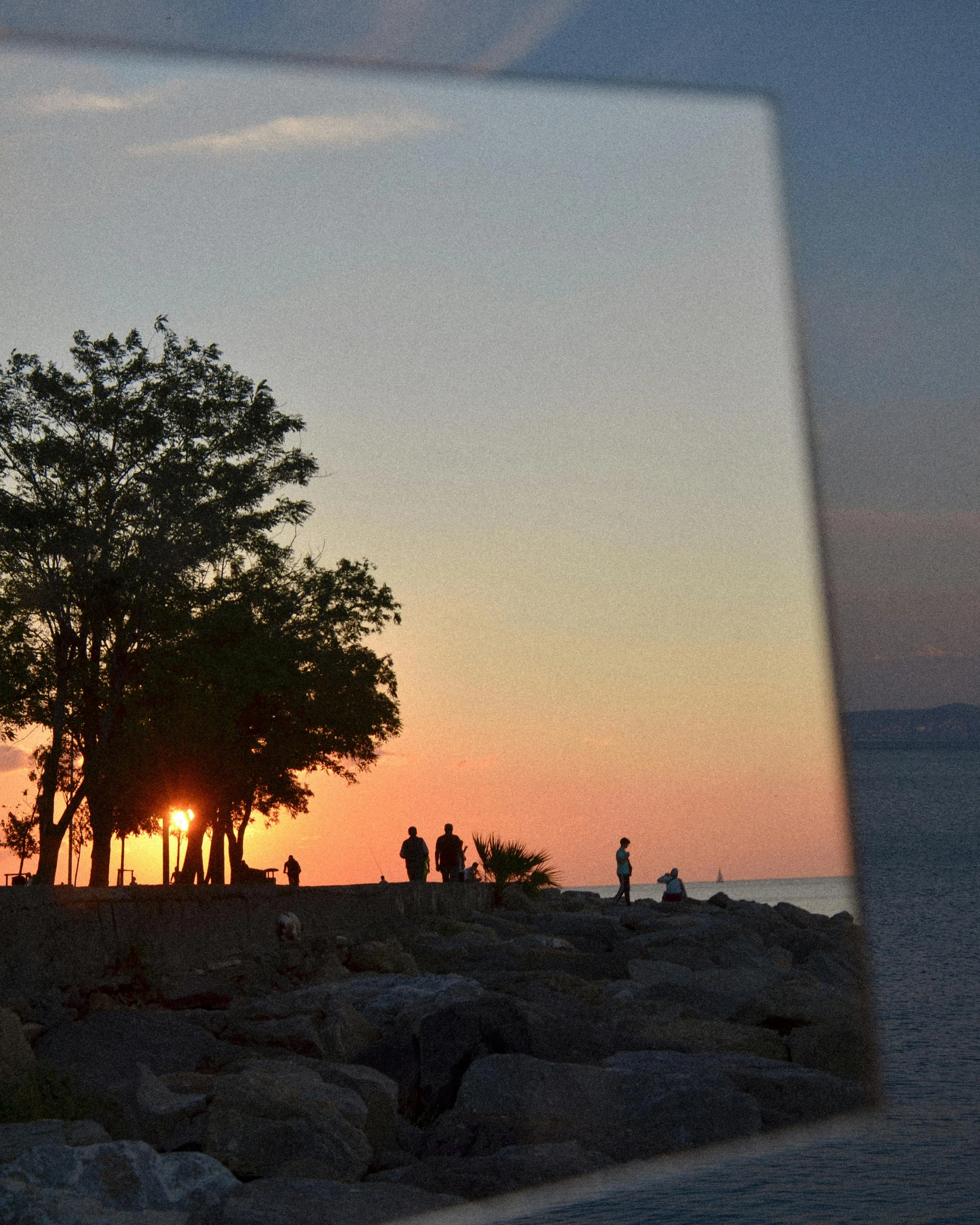 a small group of people are standing at the edge of a cliff, watching a sunset