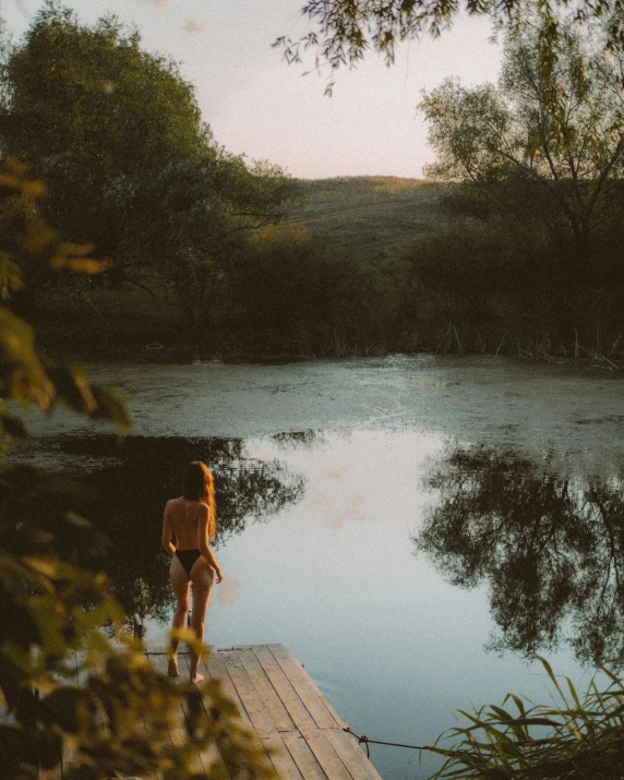 a person in swimsuit by the water and trees