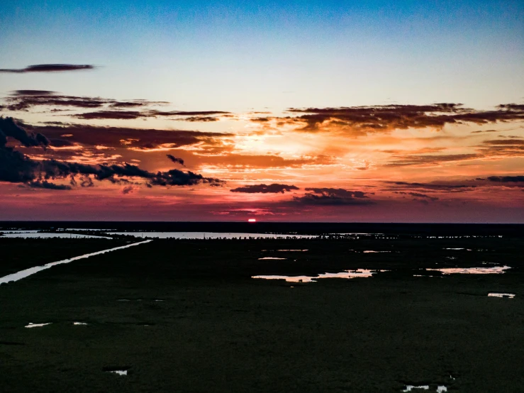 sunset seen from an ocean shore in the foreground