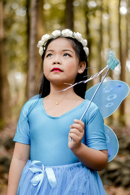 a girl in fairy costume holds onto a propellor