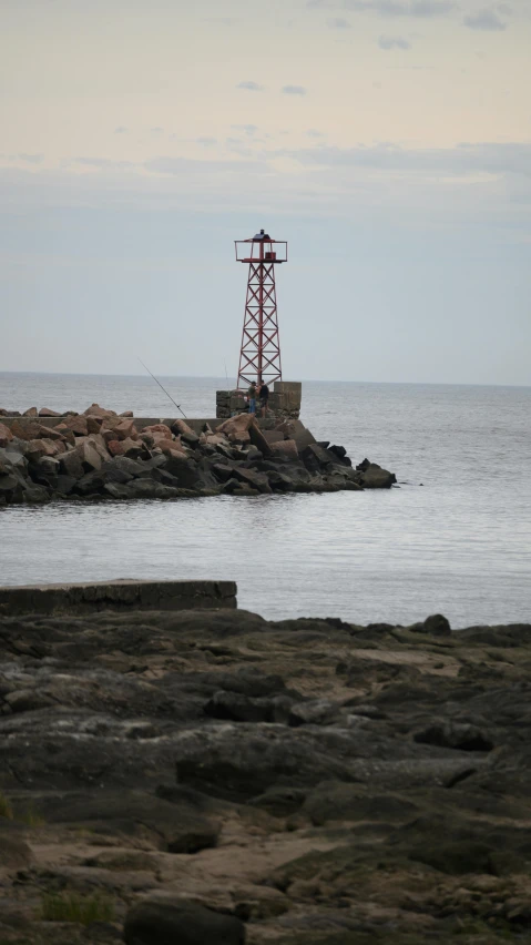 there is a lighthouse in the distance with rocky shoreline