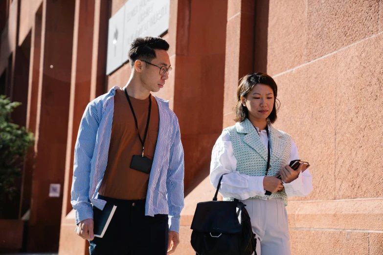 two people standing near each other holding handbages