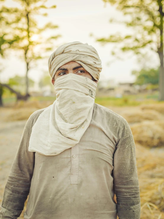 a man in a white turban walks down a dirt road