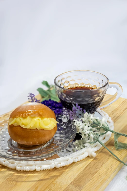 a coffee cup next to a small bun on a glass plate