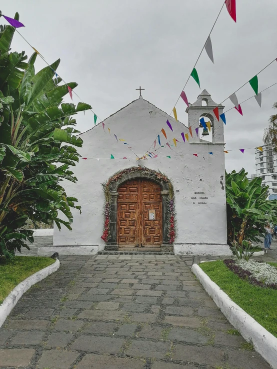 a church sits in the grass with colorful flags flying