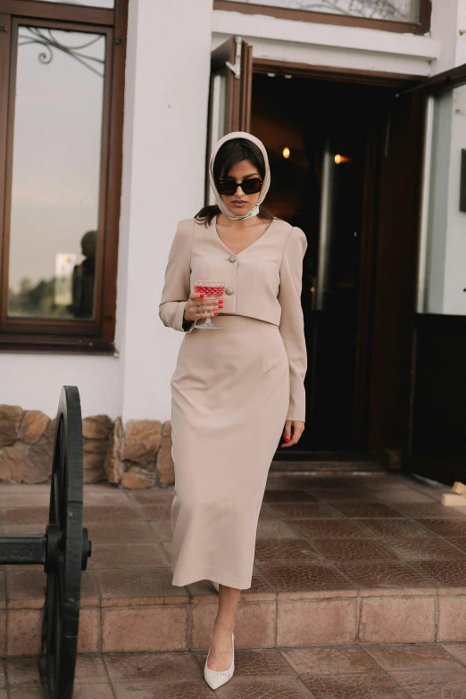 a woman walking down a stone step holding a red beverage