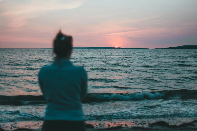 a person on the beach with water and land in the background