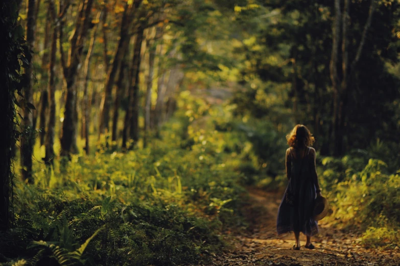 a young woman walking on a path through a forest