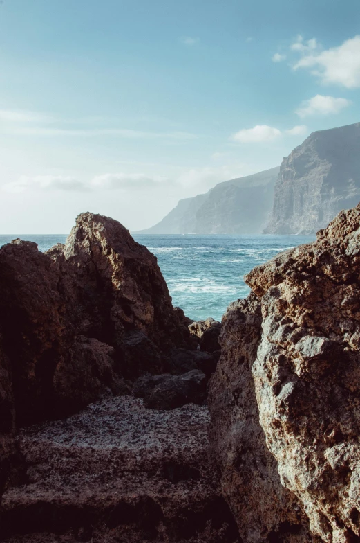 two people walking in a rocky area overlooking the ocean