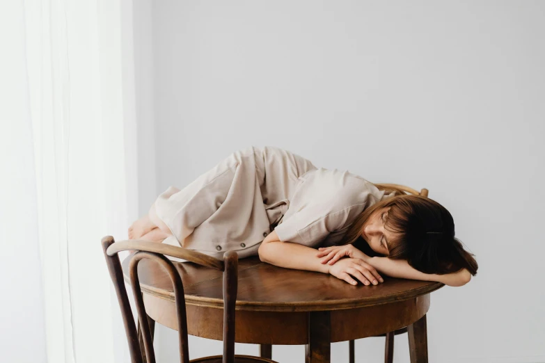 the girl is resting her head on the table