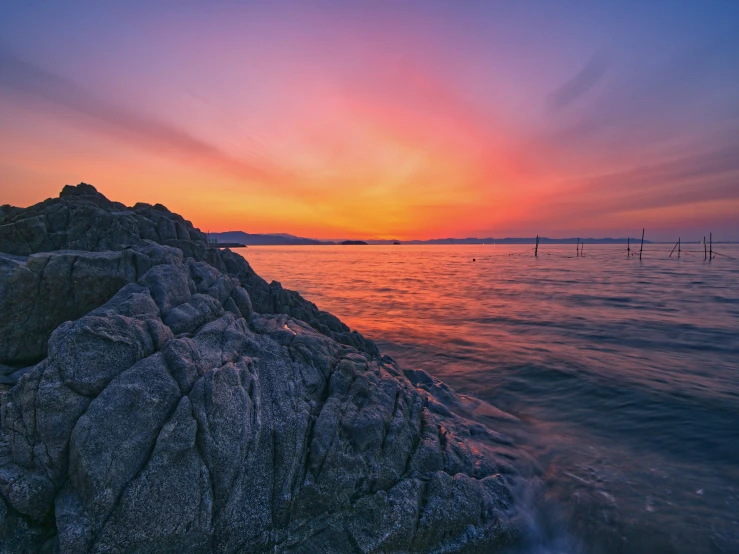 a sunset over a body of water with large rocks