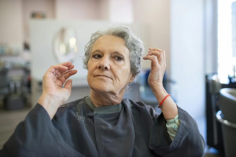 an older woman with gray hair combing her hair