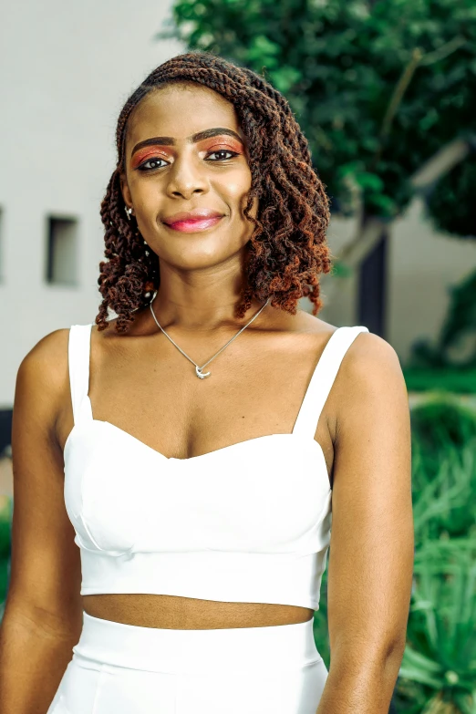 a smiling woman in white is standing outside