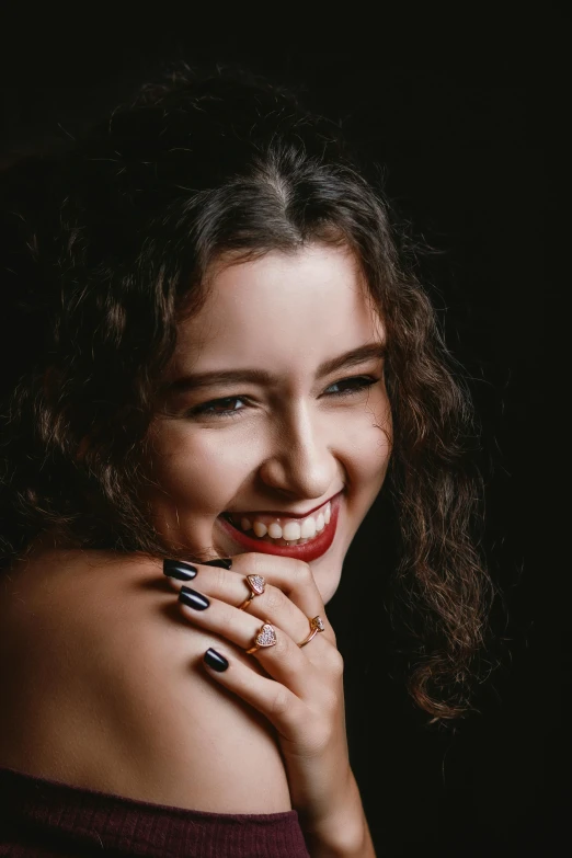 a smiling woman with nails holding her hand near her mouth