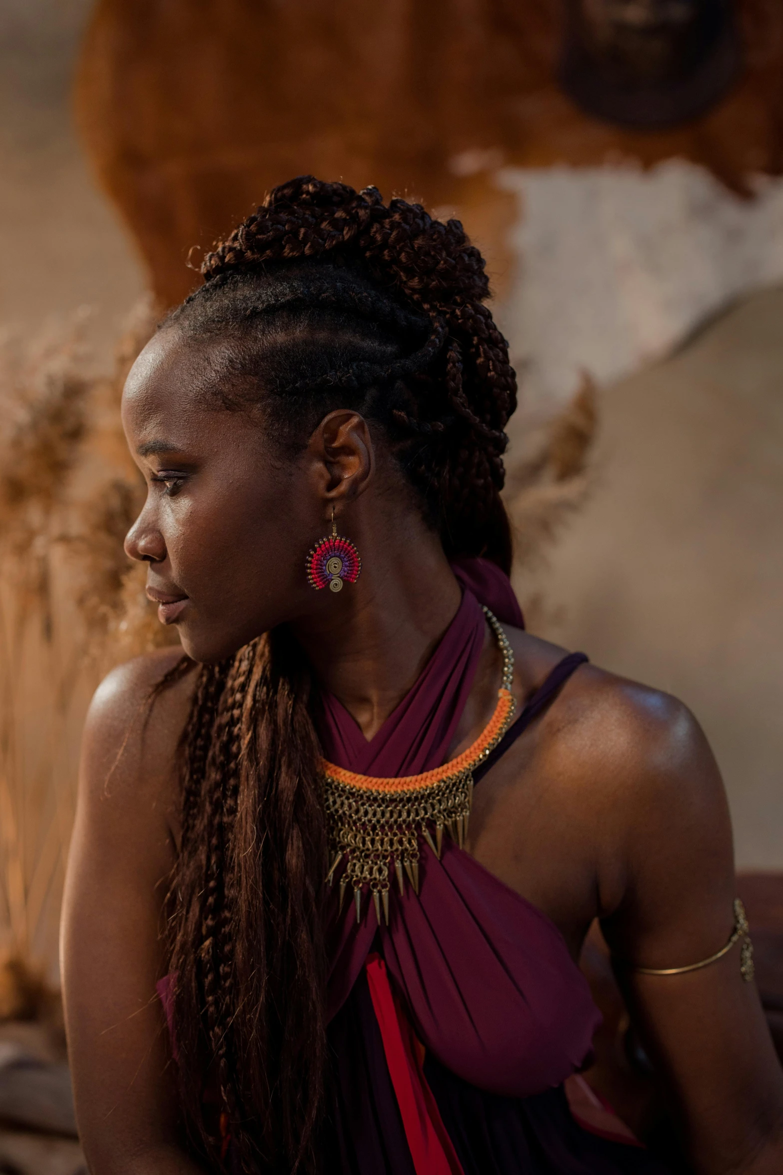 a woman sitting outside wearing large earrings and a purple dress