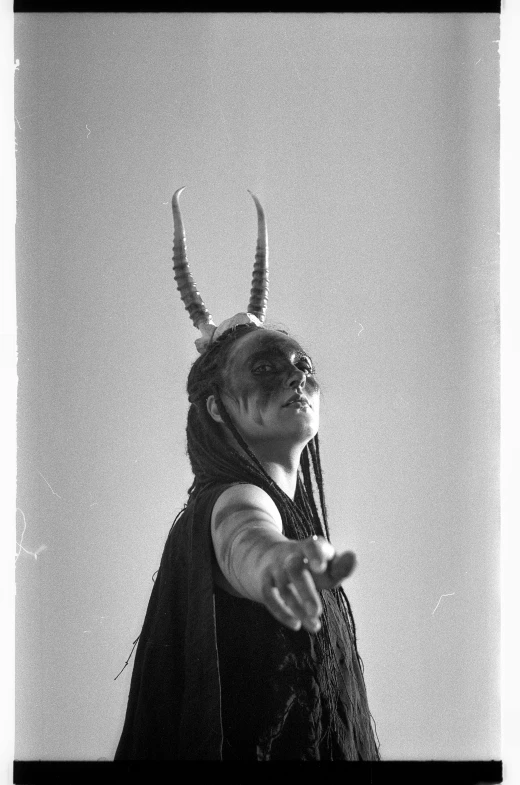 a man in a horned headgear standing and pointing