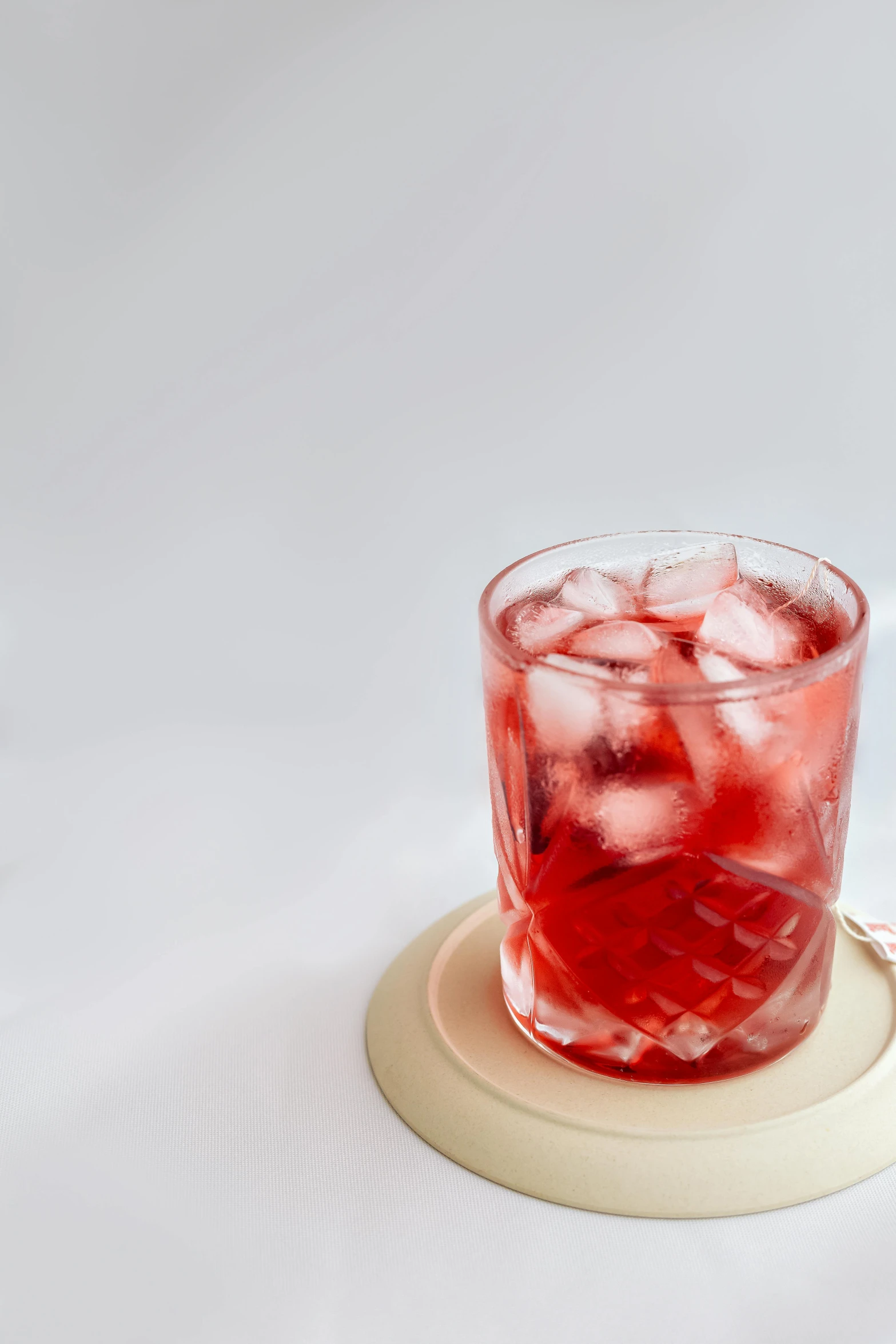 a glass of red liquid on top of a coaster