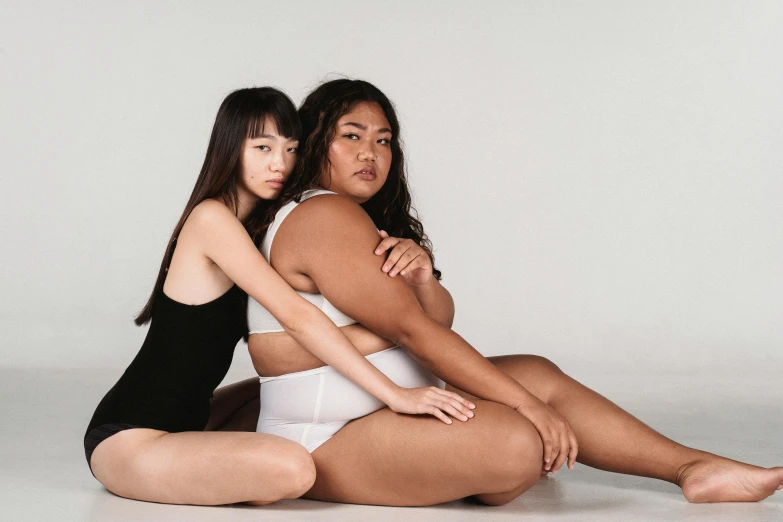 two women pose for the camera on a white surface