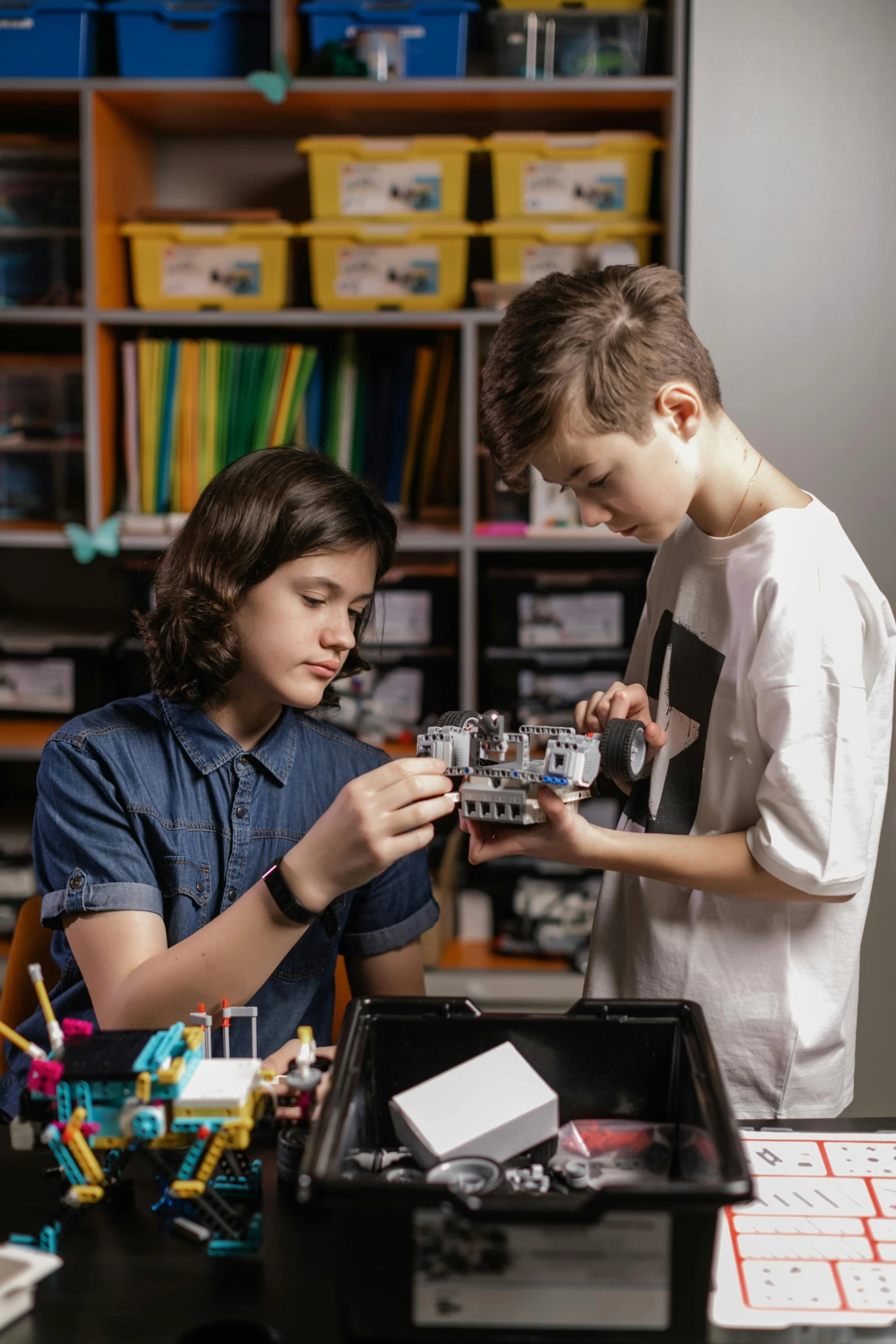 a boy and girl looking at a toy car in front of a box