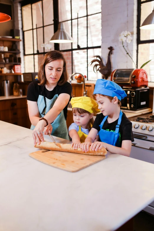 an adult and two children making pizzas in a kitchen