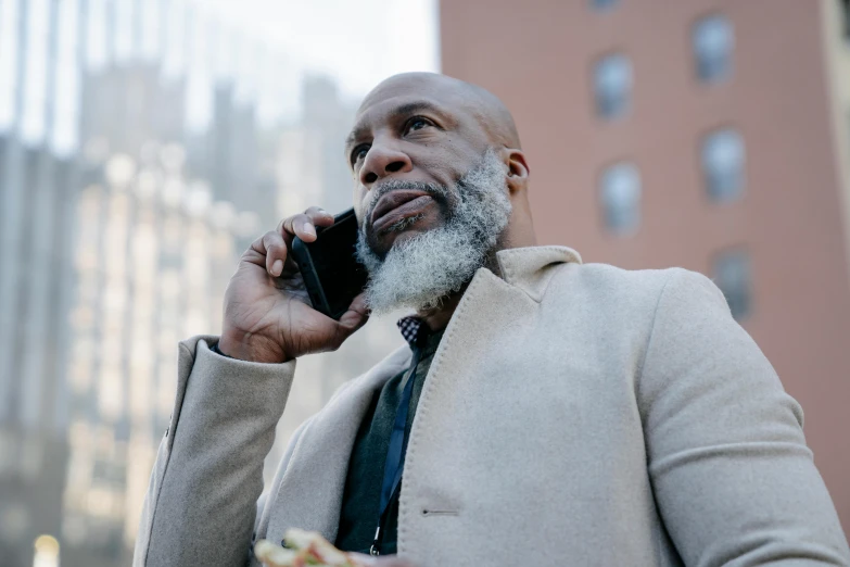 a man with a white beard and a suit is talking on his cell phone