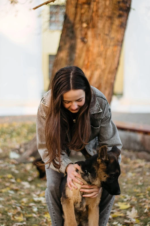 a woman kneeling down petting her dog in the park