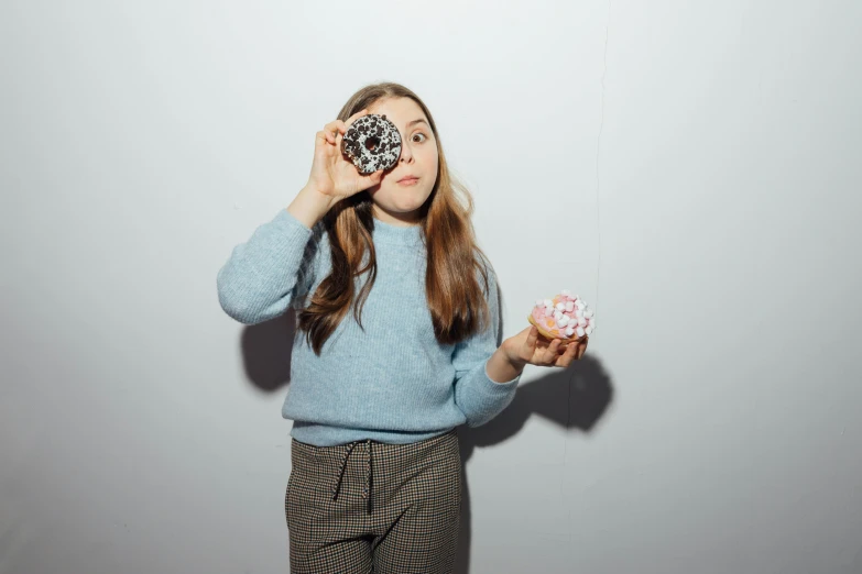 a woman holding up a doughnut in front of her eyes