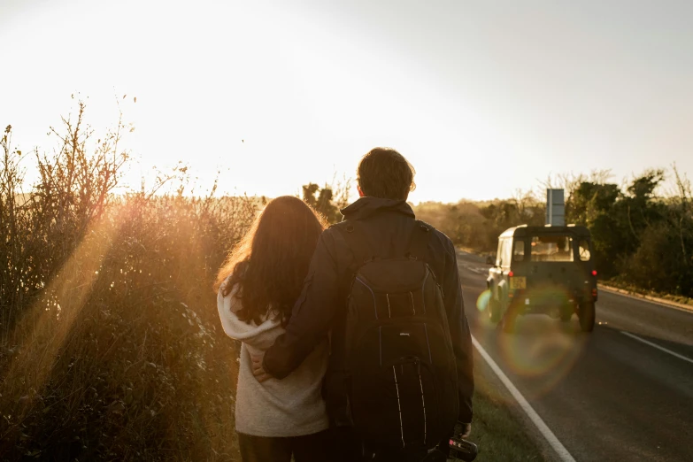 two people walk towards a car next to the highway