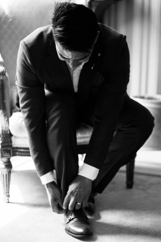 a man in a suit putting on a shoe
