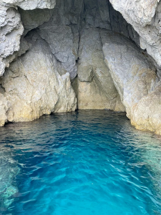 a pool in the middle of a cave with blue water