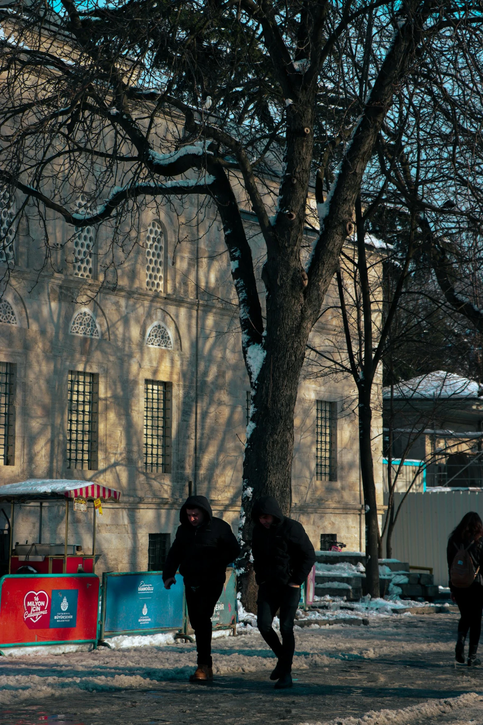 some people are walking around by a building in the snow