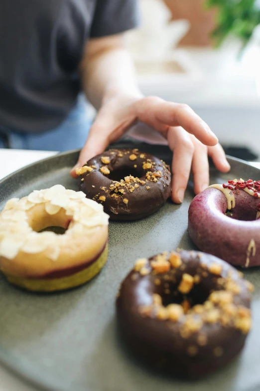 a hand is touching the donuts on a plate