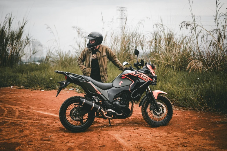 a person standing by a motorcycle parked on the side of a road