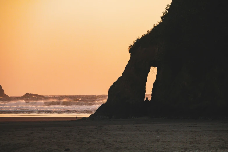 two people in front of an arch by the beach