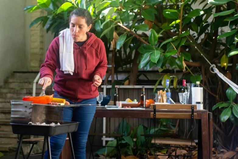 woman cooking on an outdoor grill outside in the sun