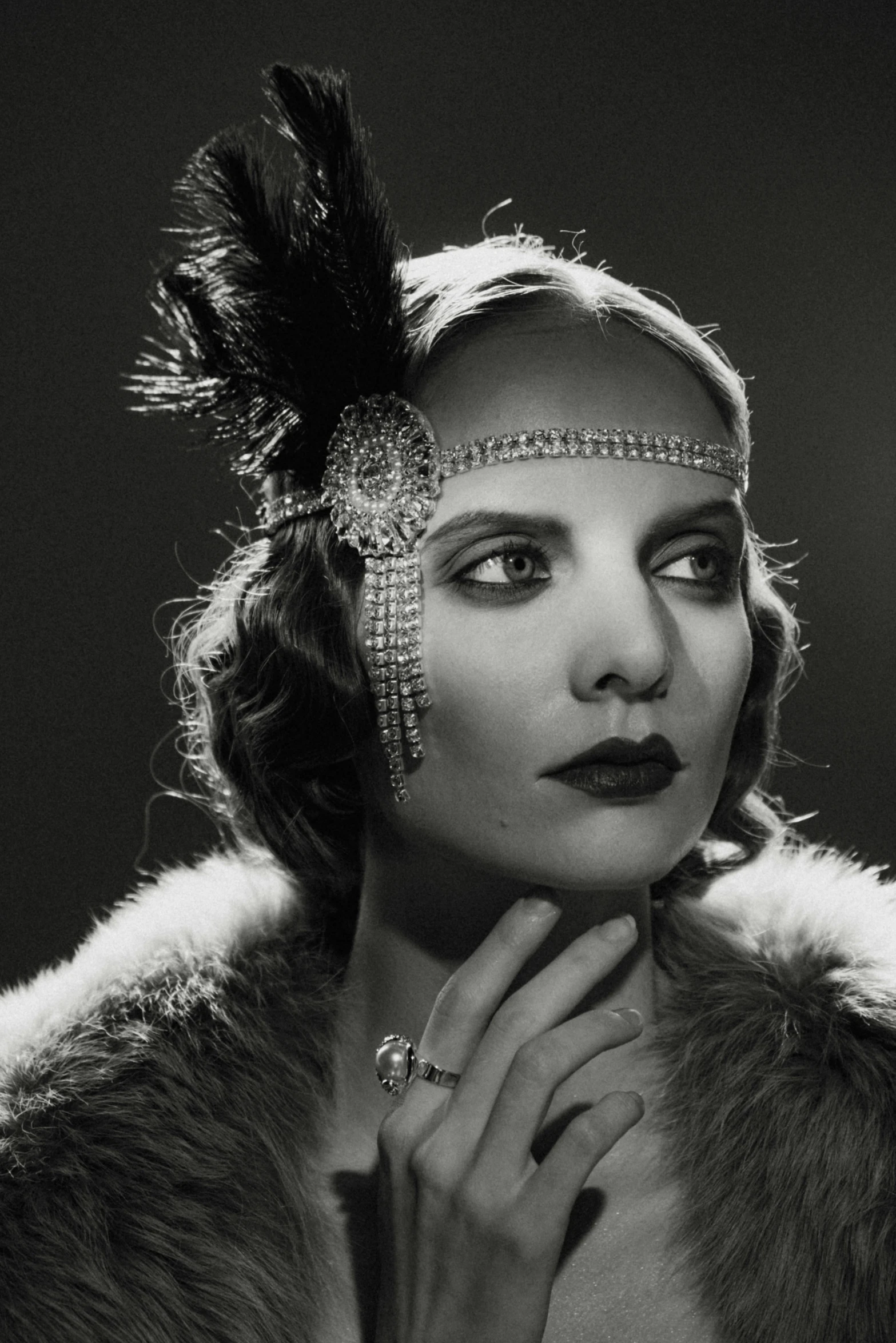 a vintage woman in a furry coat wearing a diamond headpiece and ring