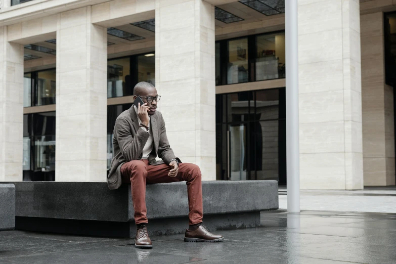 a man with a cell phone sits on a bench