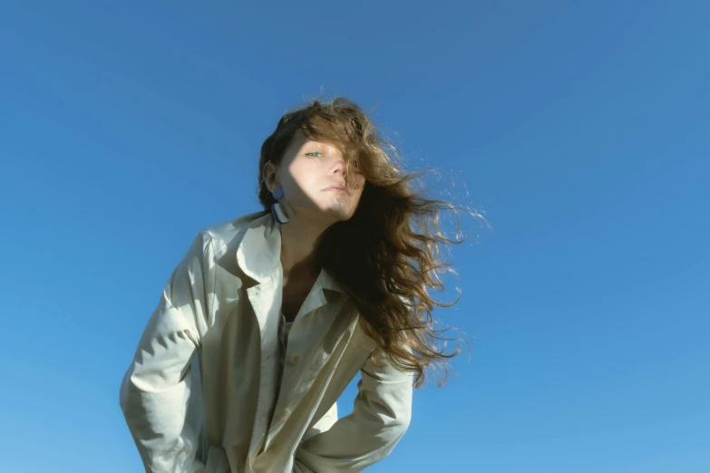 a woman is standing with her hair blowing in the wind