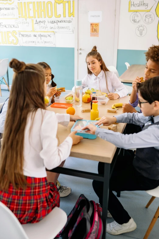 a girl with long brown hair eating at a table