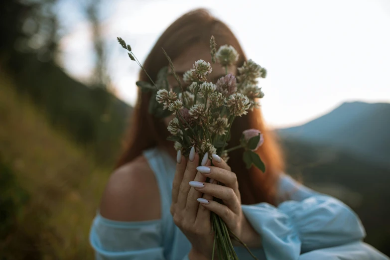 a  holds flowers in one hand and is looking at the viewer